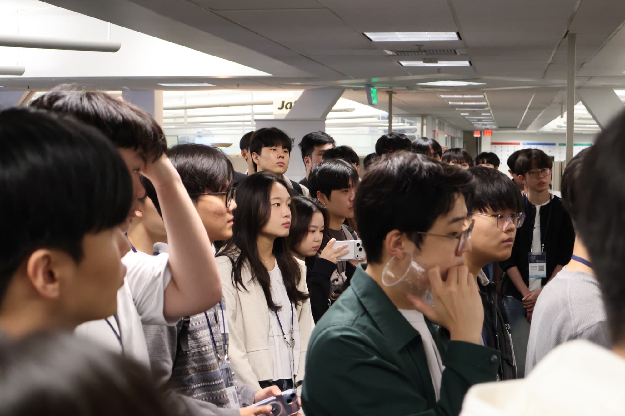 A group of program participants listening closely during a tour of a tech company's office.