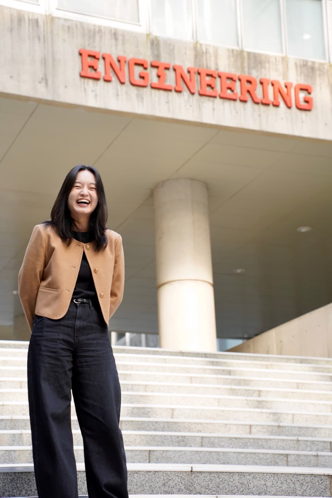 Nicole laughing on the steps beneath a large "ENGINEERING" sign outside the SNU College of Engineering building.