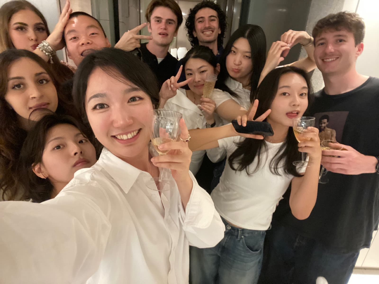 Nicole and a group of friends smiling together, holding drinks up for a close-up group photo.